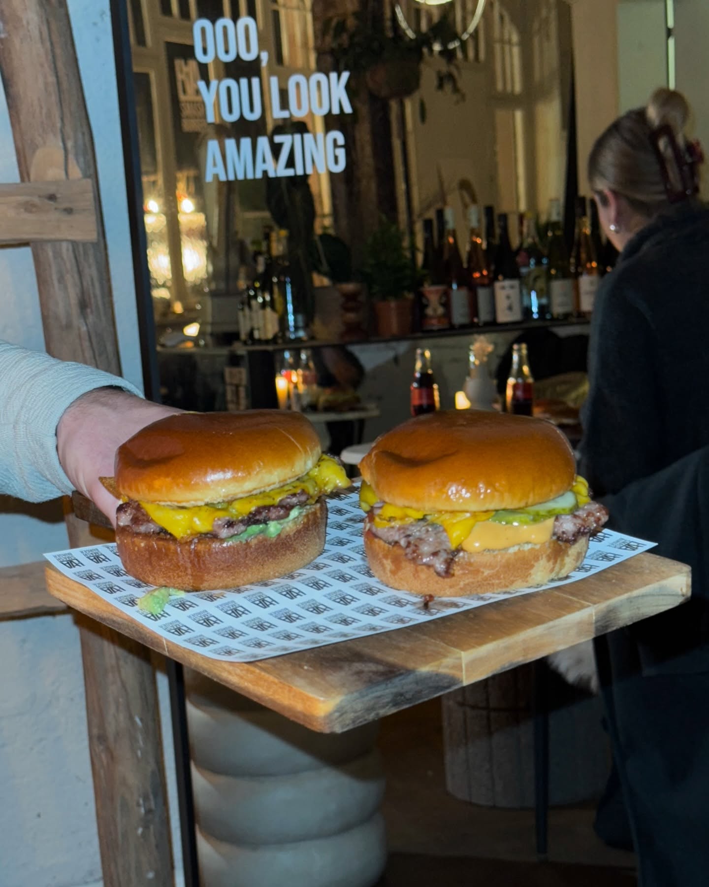 Zwei Smash Burger auf Tablett vor einem stylischen Restaurant mit „You look amazing“-Schriftzug