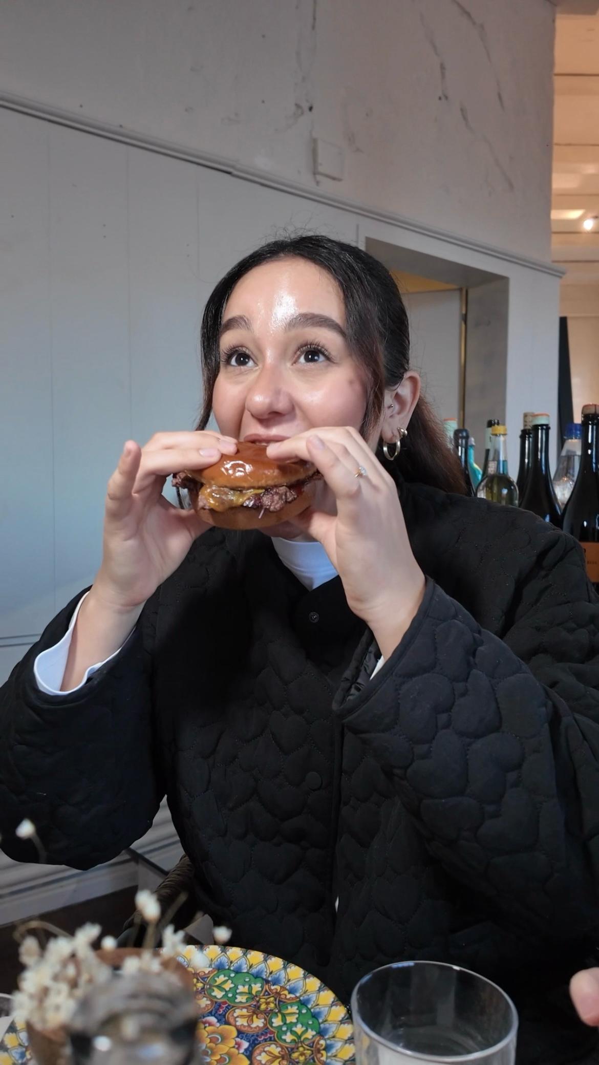Frau beißt in einen Burger in einem modernen Restaurant
