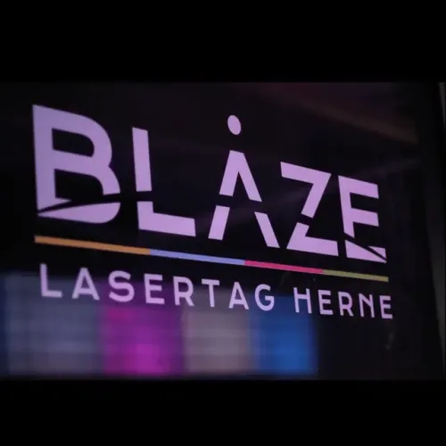 Leuchtendes Logo von BLAZE Lasertag Herne vor dunklem Hintergrund mit Farbakzenten