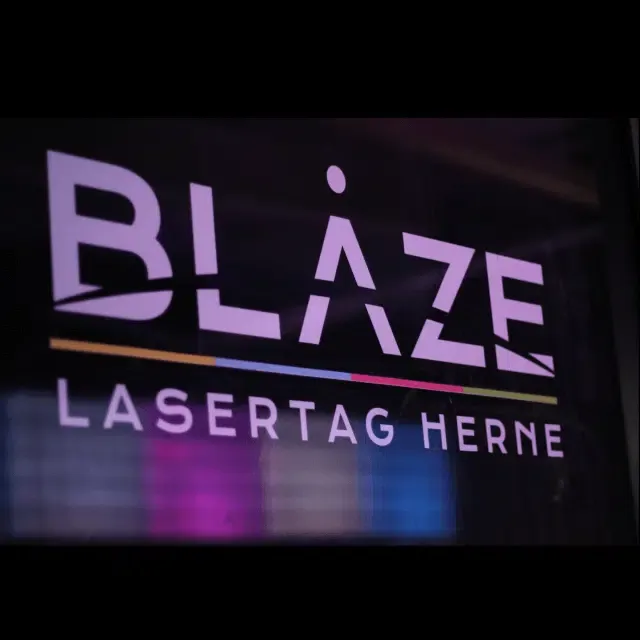 Leuchtendes Logo von BLAZE Lasertag Herne vor dunklem Hintergrund mit Farbakzenten