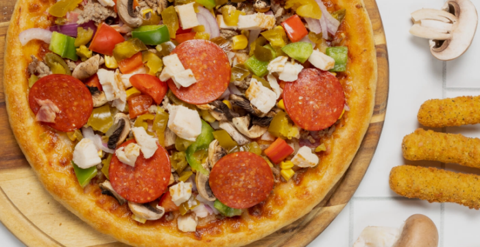 Bunte Pizza mit Peperoni, Paprika, Pilzen, Zwiebeln und Käsewürfeln auf einem Holzbrett