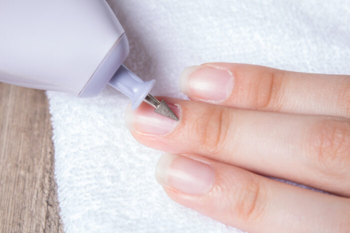 Nahaufnahme einer Maniküre, bei der die Nagelhaut mit einem Fräser entfernt wird