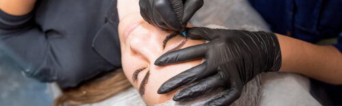 Präzise Microblading-Behandlung der Augenbrauen mit Handschuhen und feinem Werkzeug