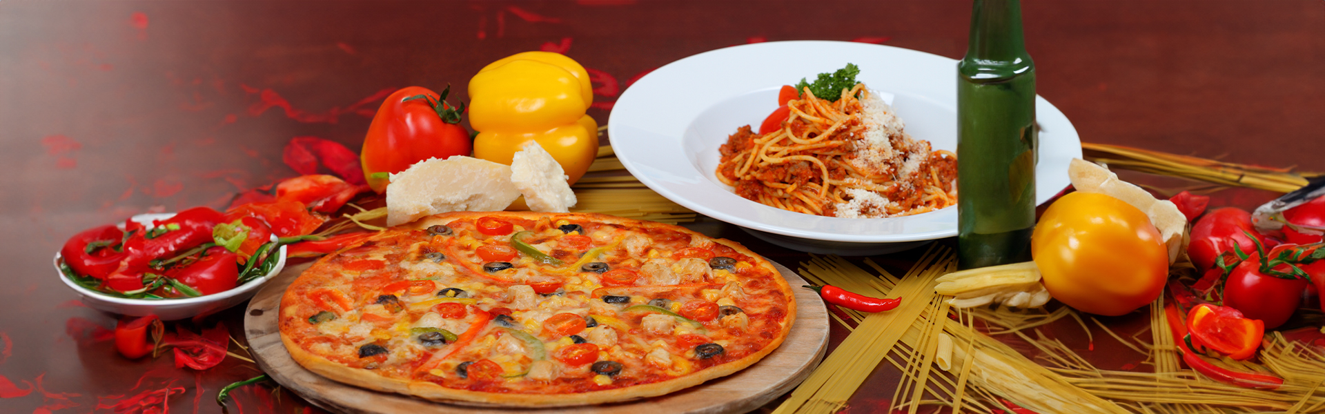 Frische Pizza mit Gemüse und ein Teller Spaghetti im Pizza Paradies Köln