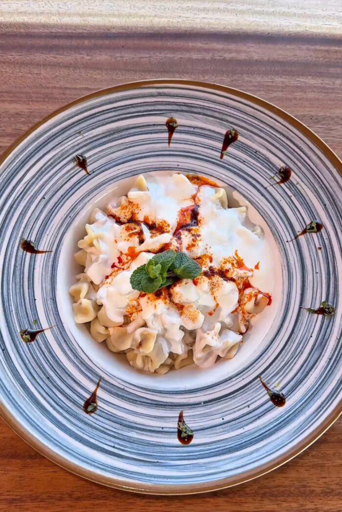 Manti mit Joghurt und Paprikabutter, serviert auf einem dekorativen Teller