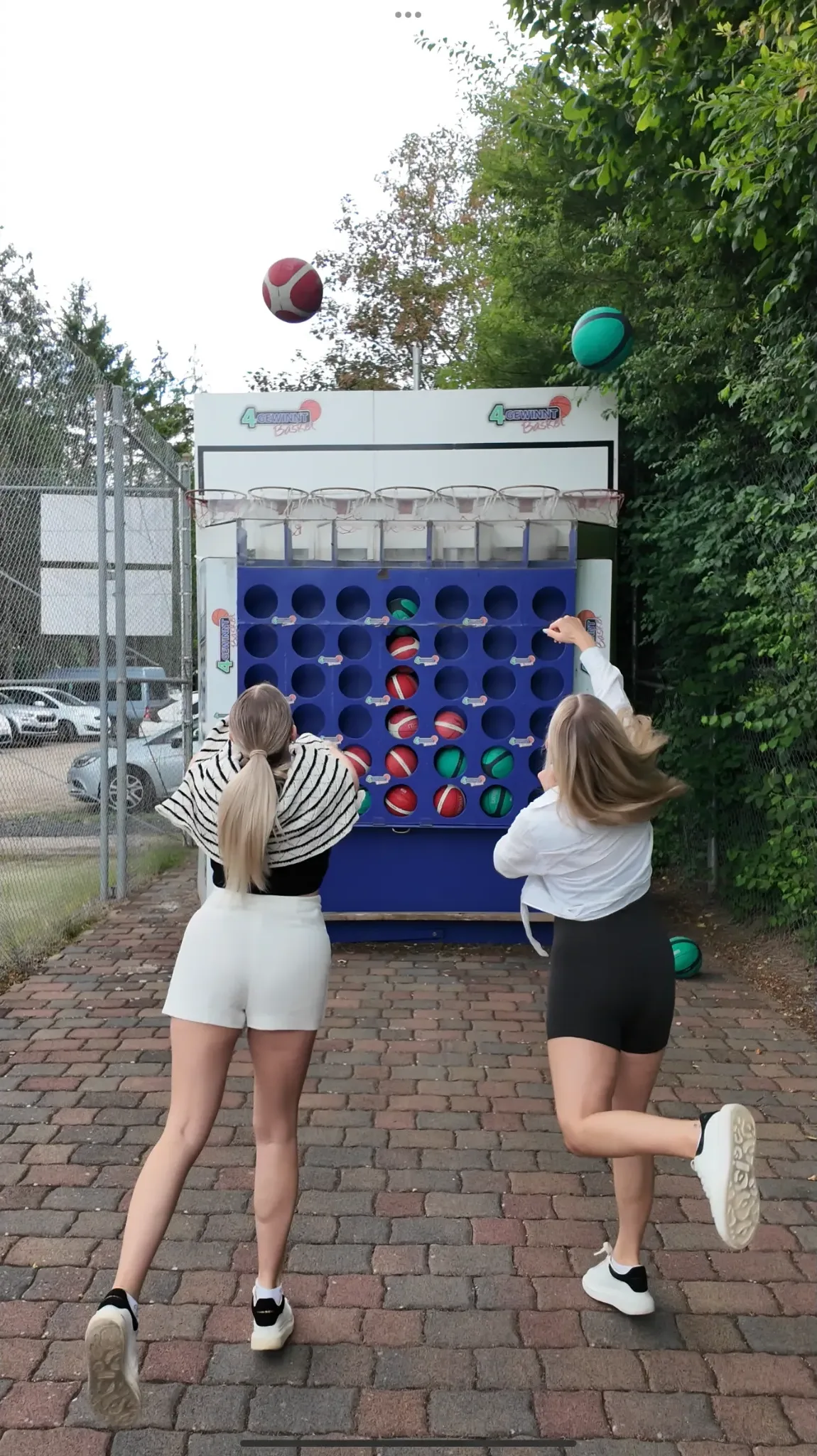 Zwei junge Frauen werfen Bälle auf eine große bunte Reaktionswand im Freien auf dem Sport- und Freizeitpark in Limburg-Linter