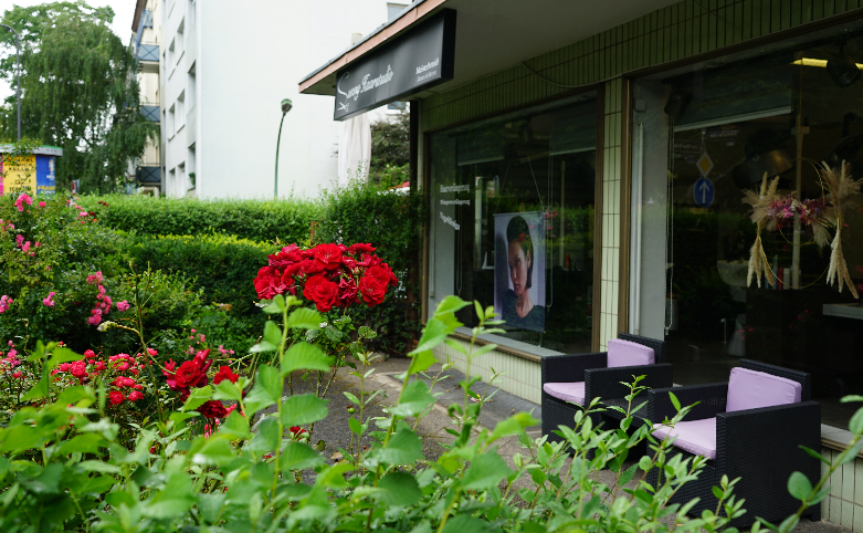 Außenansicht des Sunny Friseursalons in Frankfurt mit Blumen im Vordergrund