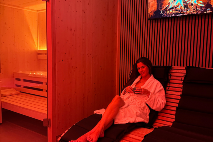Frau im Bademantel entspannt im Ruhebereich vor der Sauna beim Therapieteam Rheine