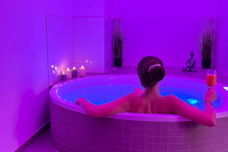 Frau genießt ein stimmungsvolles Entspannungsbad mit Kerzenlicht und Farbbeleuchtung beim Therapieteam Rheine