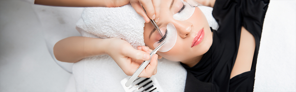 Nahaufnahme einer professionellen Wimpernverlängerung mit Pinzette