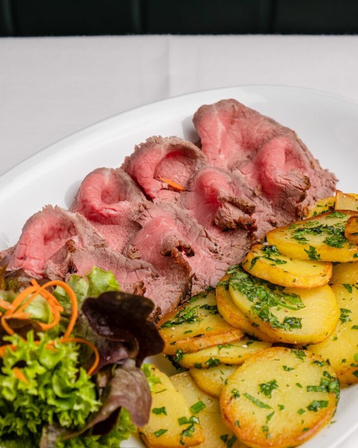 Bratkartoffeln mit Roastbeef und gemischtem Salat auf einem weißen Teller im Café Restaurant Manzini in Berlin