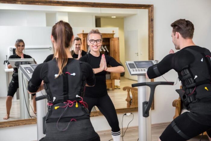 EMS-Training in einem Berliner Studio mit Trainerin und zwei Teilnehmern in spezieller Trainingskleidung
