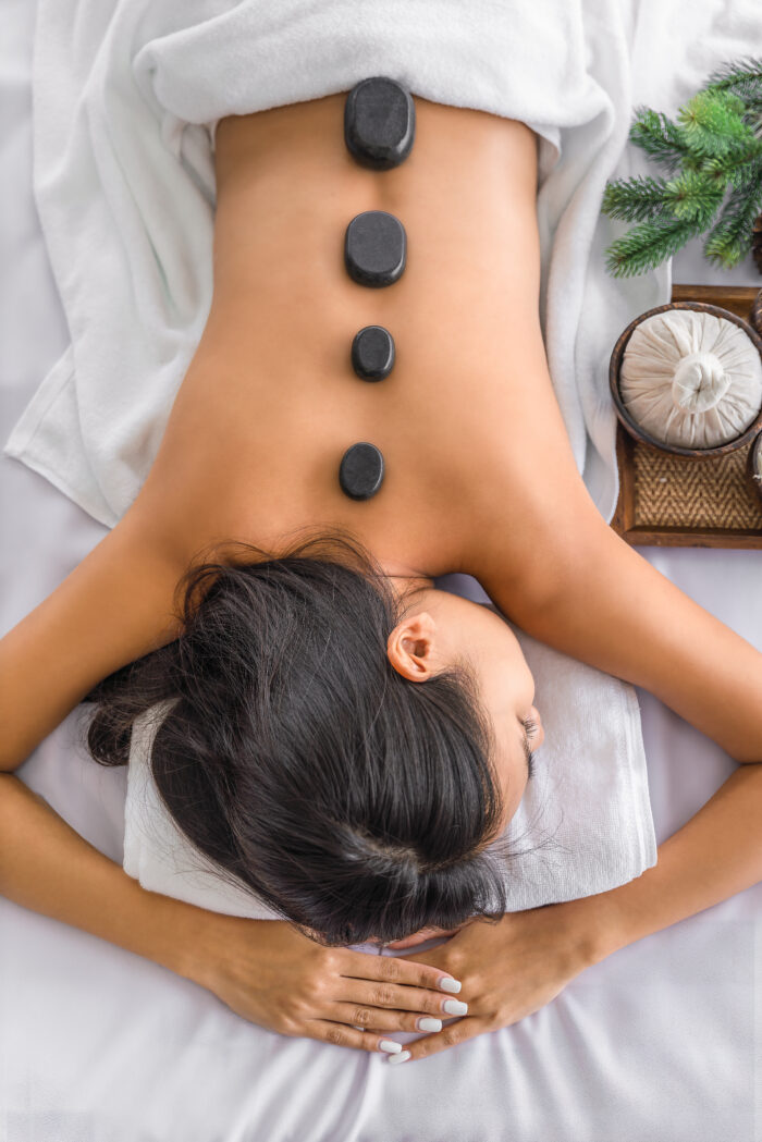 Frau bei einer Hot-Stone-Massage mit schwarzen Steinen auf dem Rücken, entspannend und wohltuend