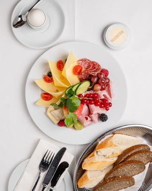 Frühstücksteller mit Käse, Schinken, Salami, frischem Obst und Brotauswahl im Manzini Café Berlin