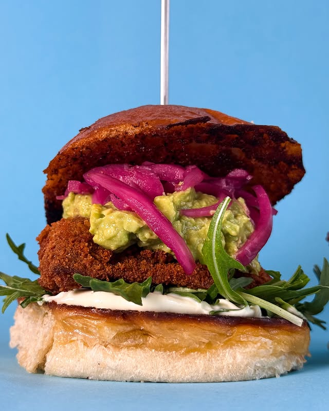 Nahaufnahme eines veganen Burgers mit Guacamole, Rucola und roten Zwiebeln bei Lia’s Kitchen Berlin