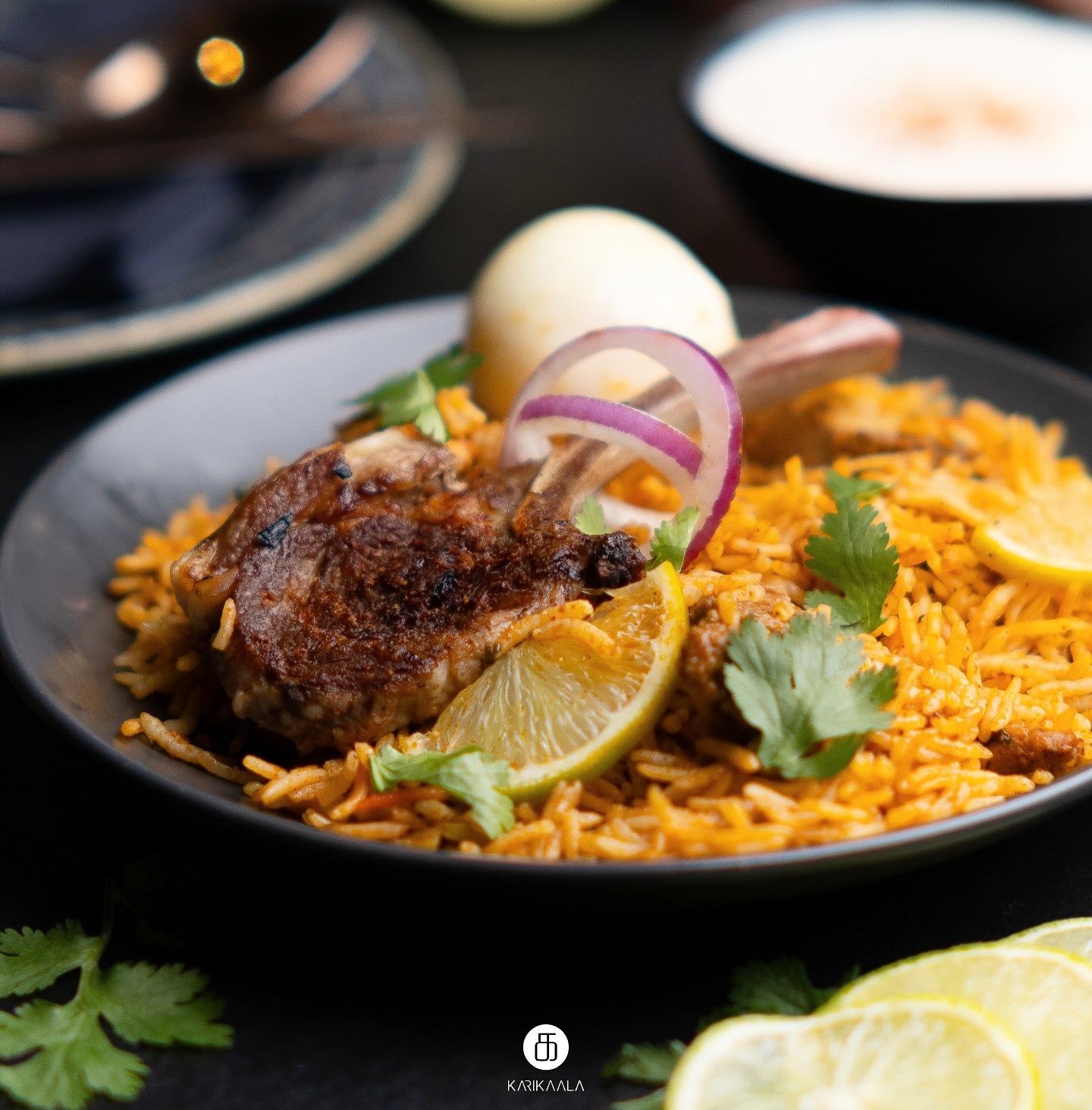 Würziges Lammgericht mit Basmatireis, Zitrone, Koriander und gekochtem Ei auf schwarzem Teller