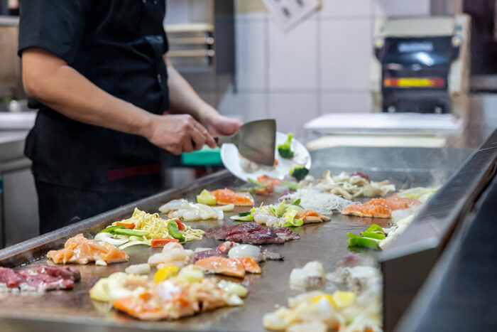 Koch bereitet frische Zutaten auf der heißen Grillplatte im Chinakrone Restaurant zu
