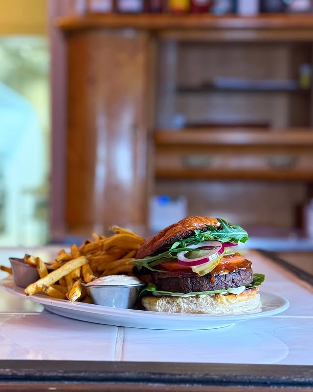 Veganer Burger mit frischem Gemüse, serviert mit knusprigen Pommes und Dip bei Lia’s Kitchen in Berlin