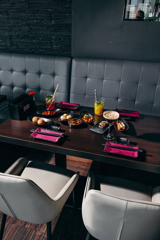 Tisch mit verschiedenen Tapas-Gerichten und Drinks im Restaurant Mukii Dortmund, serviert in modernen Schalen mit lilafarbenen Servietten und stilvollem Ambiente