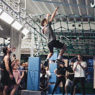 Junger Mann hangelt sich durch den Ninja-Parcours bei Ninja Skillz in Weiterstadt, beobachtet von einer Gruppe Zuschauer