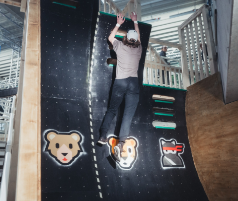 Teilnehmer erklimmt eine steile Warped Wall im Ninja Skillz Park in Weiterstadt mit Tier- und Ninja-Symbolen