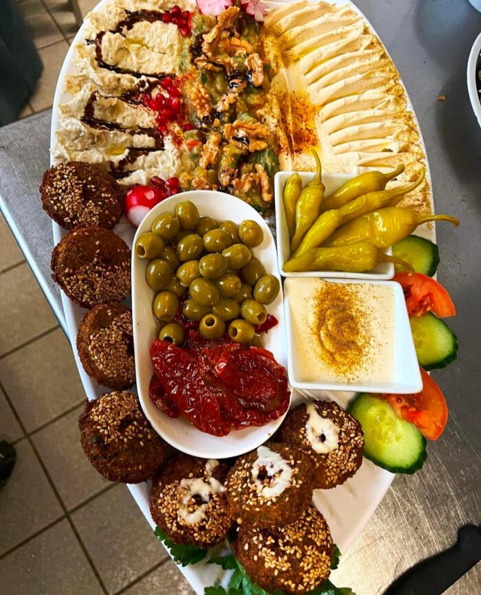 Orientalisches Frühstück im Café Morgenlicht in Berlin mit Hummus, Falafel, Oliven, Tahini, Baba Ghanoush und frischem Gemüse auf einem weißen Servierteller