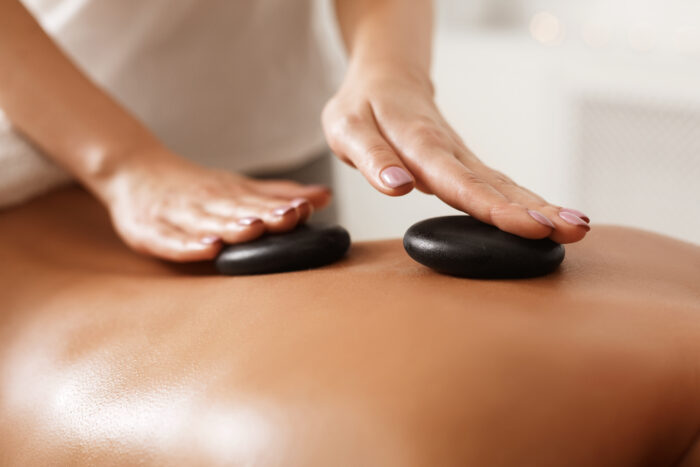 Therapeutin legt warme Lavasteine auf den Rücken während einer Hot-Stone-Massage