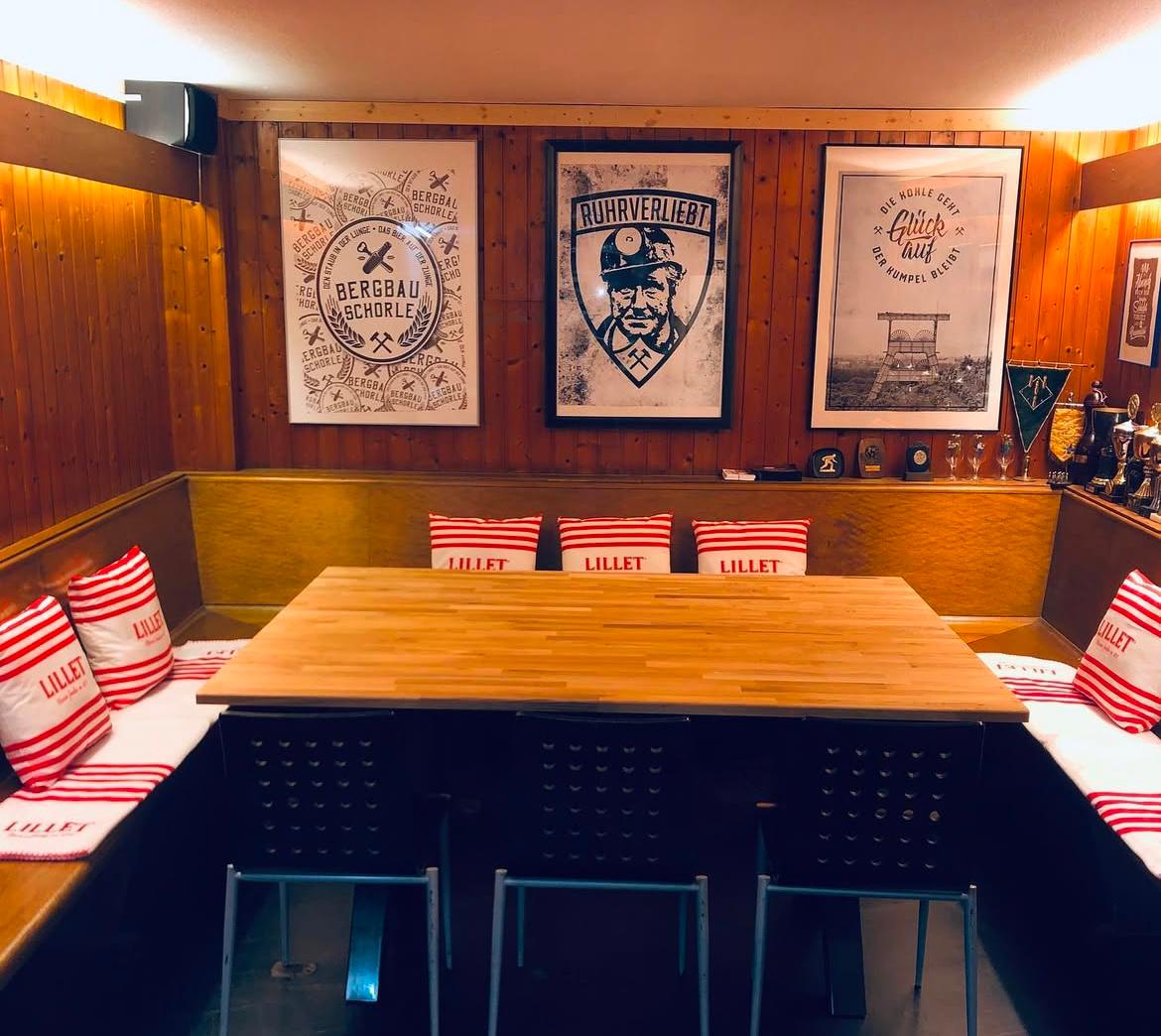 Gemütliche Sitzecke mit Holztisch im Kegelbereich der 11 Freunde Bar Essen