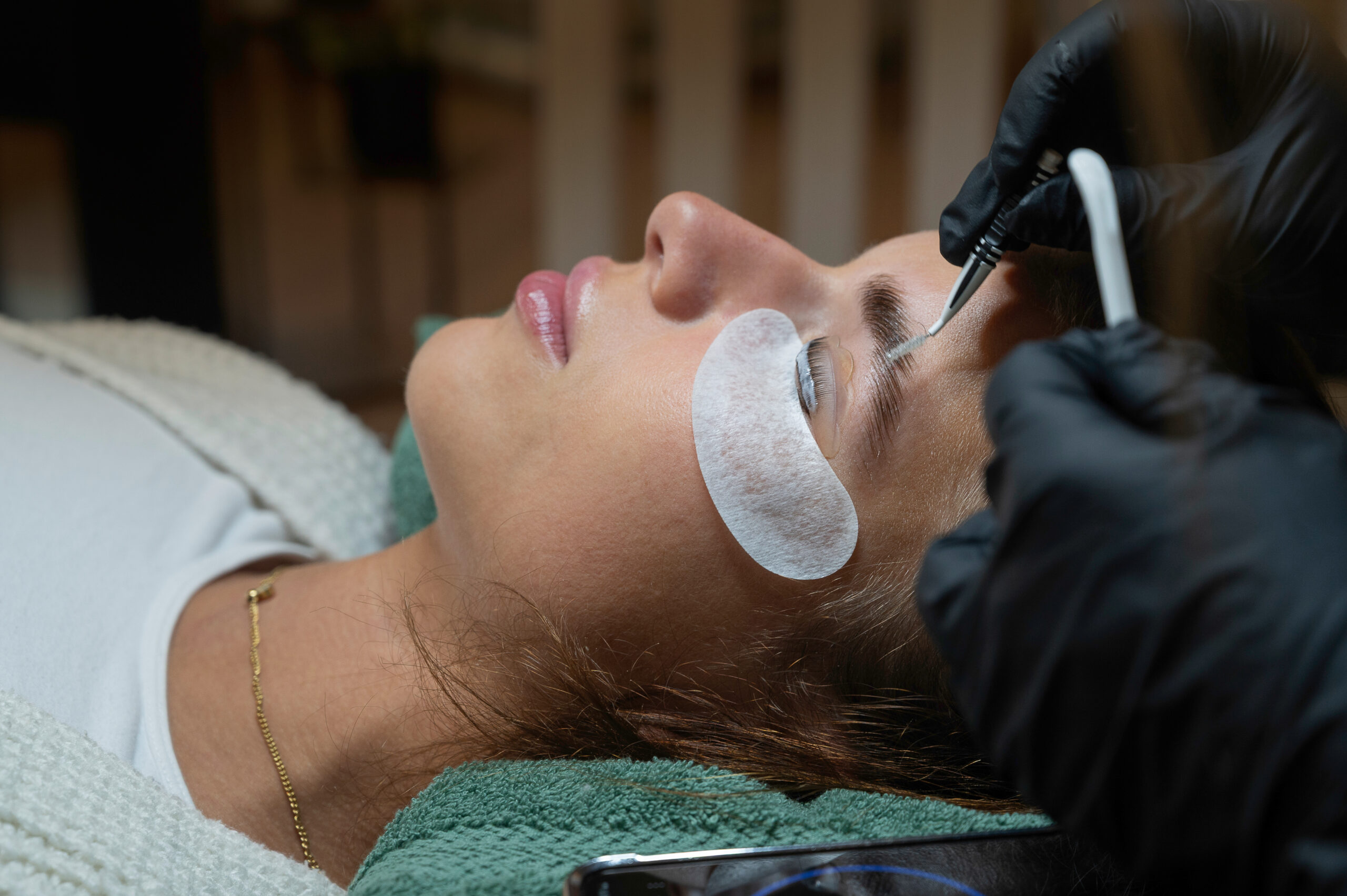 Präzises Augenbrauenlifting mit Pinzette und Pflegepad während der Behandlung