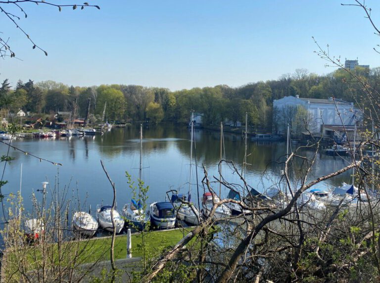 Blick auf den Stößensee mit Booten und der Anlage der Bootsschule und Charter Berlin