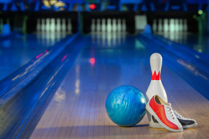 Blaue Bowlingkugel, rote und weiße Bowlingschuhe und ein Bowling-Pin auf einer Bowlingbahn
