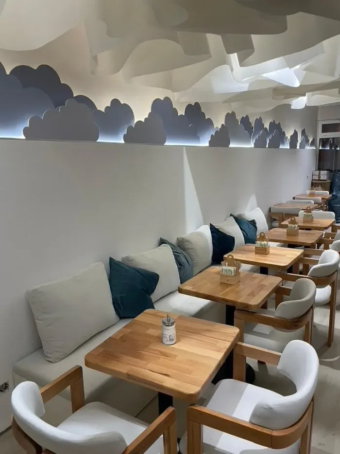 Modernes und gemütliches Café-Ambiente mit Holztischen und Wolken-Dekor im Cloudy Caffee Dortmund