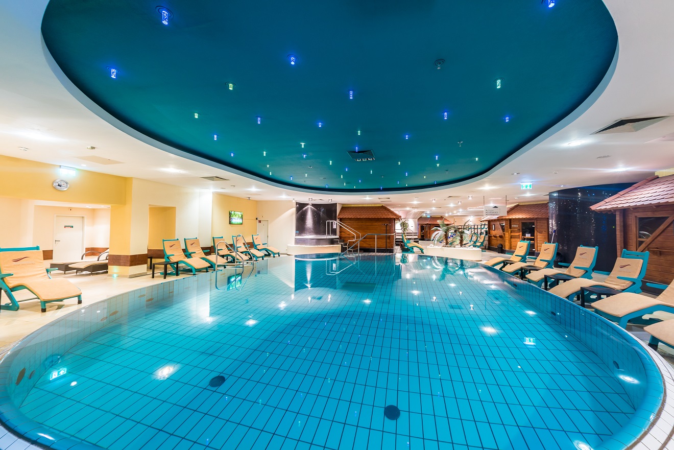 Beleuchtetes Innenbecken im Mauritius Hotel & Therme mit Liegen und Sternenhimmel-Decke