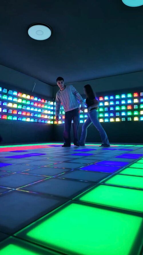 Zwei Personen spielen auf einem leuchtenden, interaktiven Boden mit bunten LED-Feldern in der Shangrila Schwelm Arena