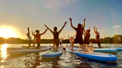 Gruppe beim Stand-up-Pilates auf dem Halterner See bei Sonnenuntergang mit Paddel