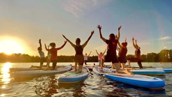 Gruppe beim Stand-up-Pilates auf dem Halterner See bei Sonnenuntergang mit Paddel