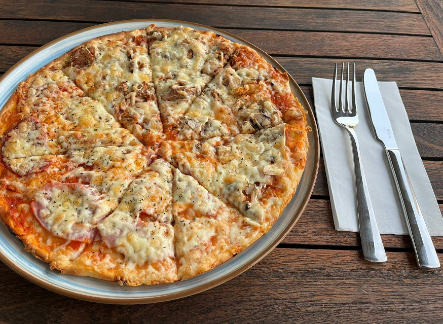 Frisch gebackene Pizza mit Käse und Champignons auf einem Holztisch bei Buonissimo Krefeld