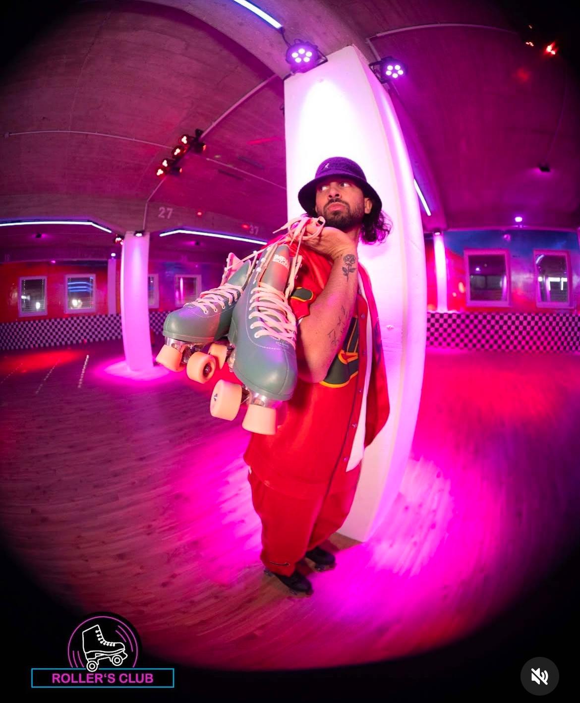 Roller Skater mit Retro-Outfit und Rollschuhen im Rollers Club Köln bei pinkem Licht