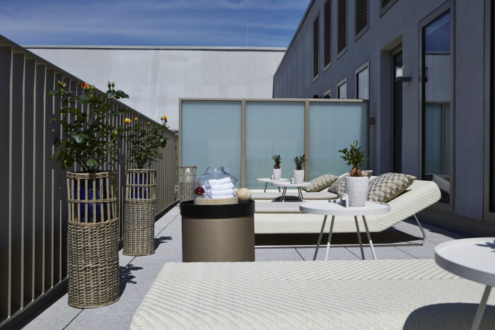 Sonnige Außenterrasse mit stilvollen Liegen und Pflanzen in der Sky Spa & Fitnesslounge Berlin