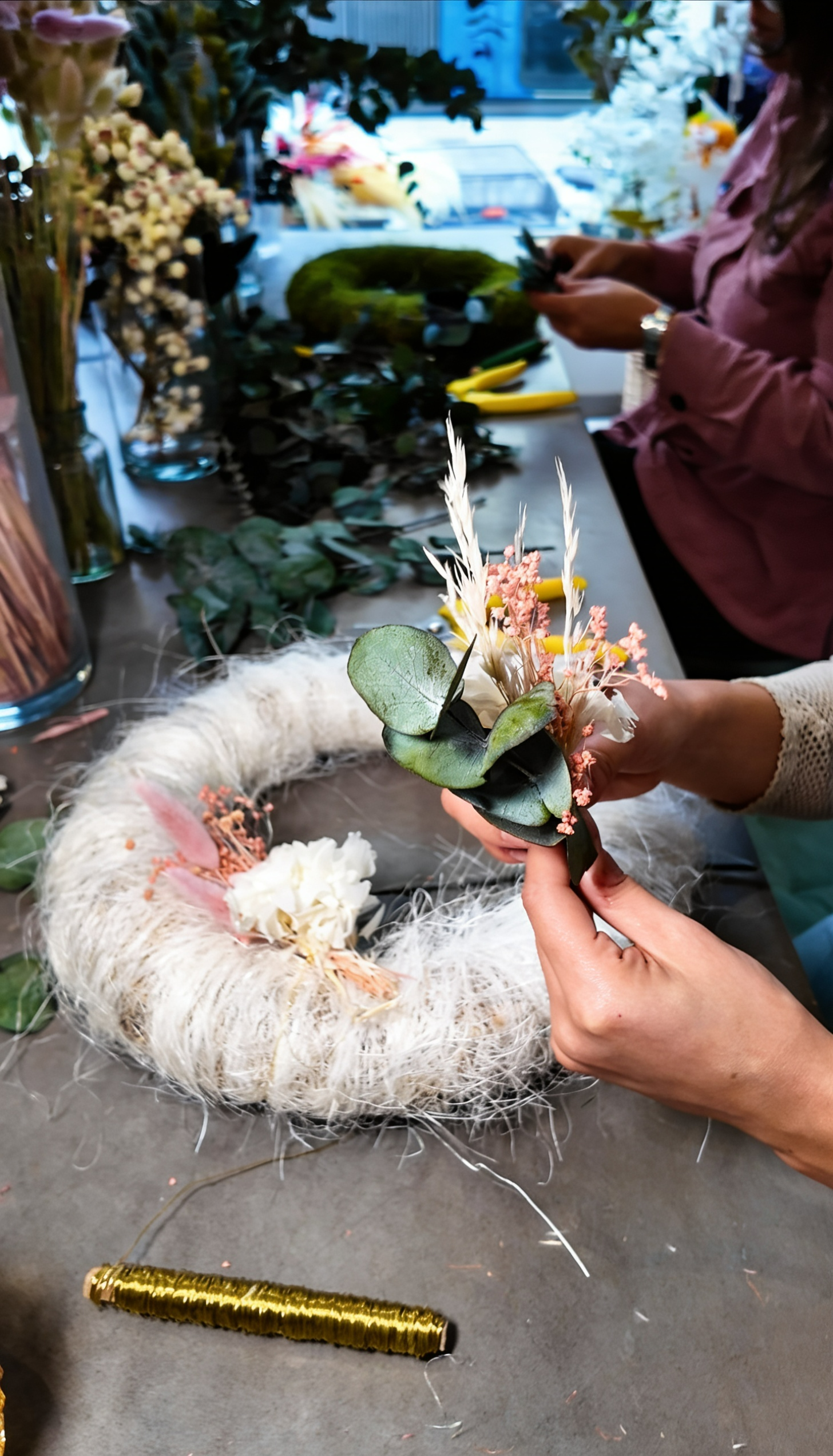 Teilnehmerin gestaltet einen Adventskranz bei Münchner Blumenmadl'n in München – kreativer Workshop mit Tannengrün, Trockenblumen und Floristikmaterialien