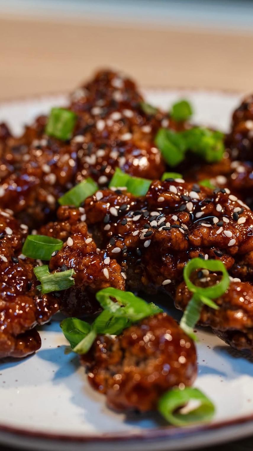 Korean Fried Chicken knusprig glasiert mit Sesam und Frühlingszwiebeln als herzhaftes Gericht bei Der Holländer in Düsseldorf.