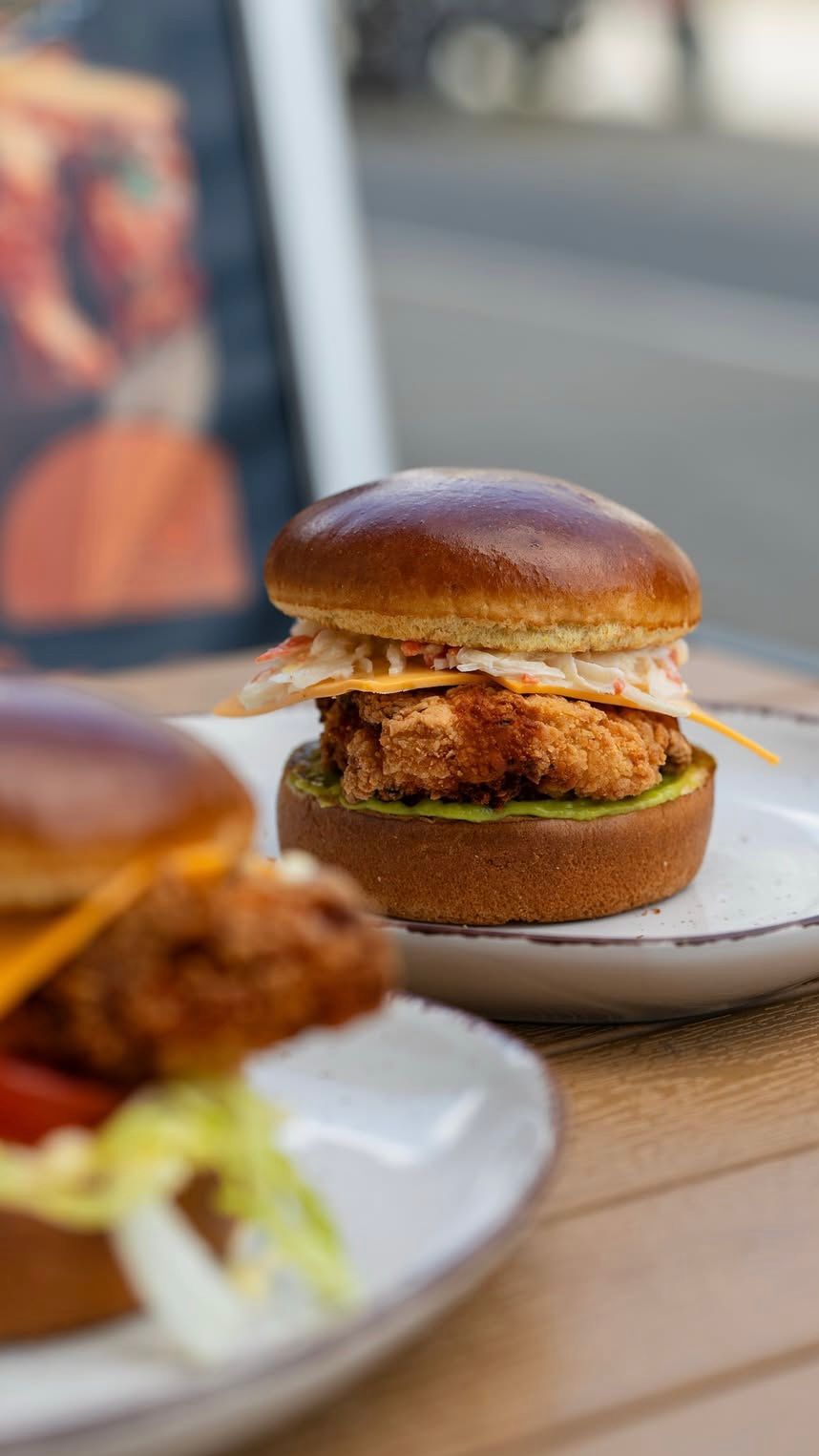 Zwei knusprige Chicken Burger mit saftigem Hähnchenfilet, Salat und Sauce serviert auf Tellern bei Der Holländer in Düsseldorf.