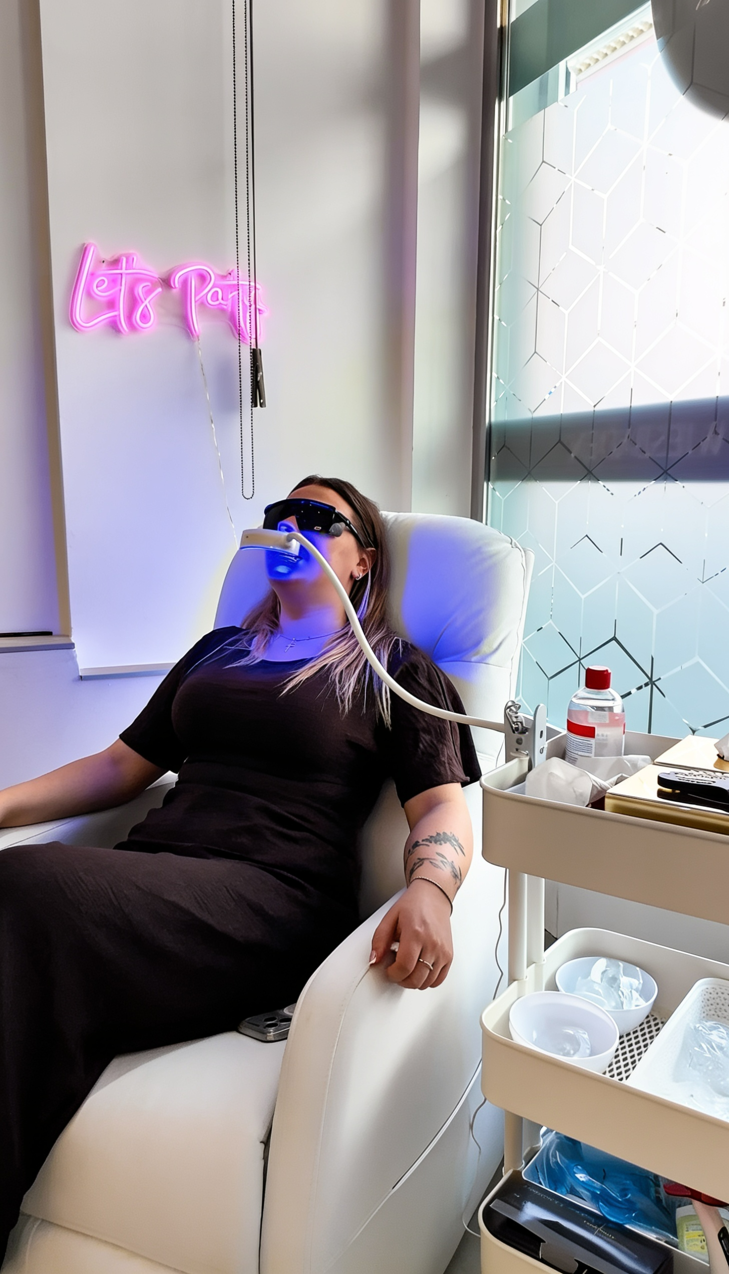 Zahnbleaching bei Piercing Clicker Wiesbaden, bei dem eine Kundin entspannt im Behandlungsstuhl liegt und die Zähne mit blauem LED Licht aufgehellt werden