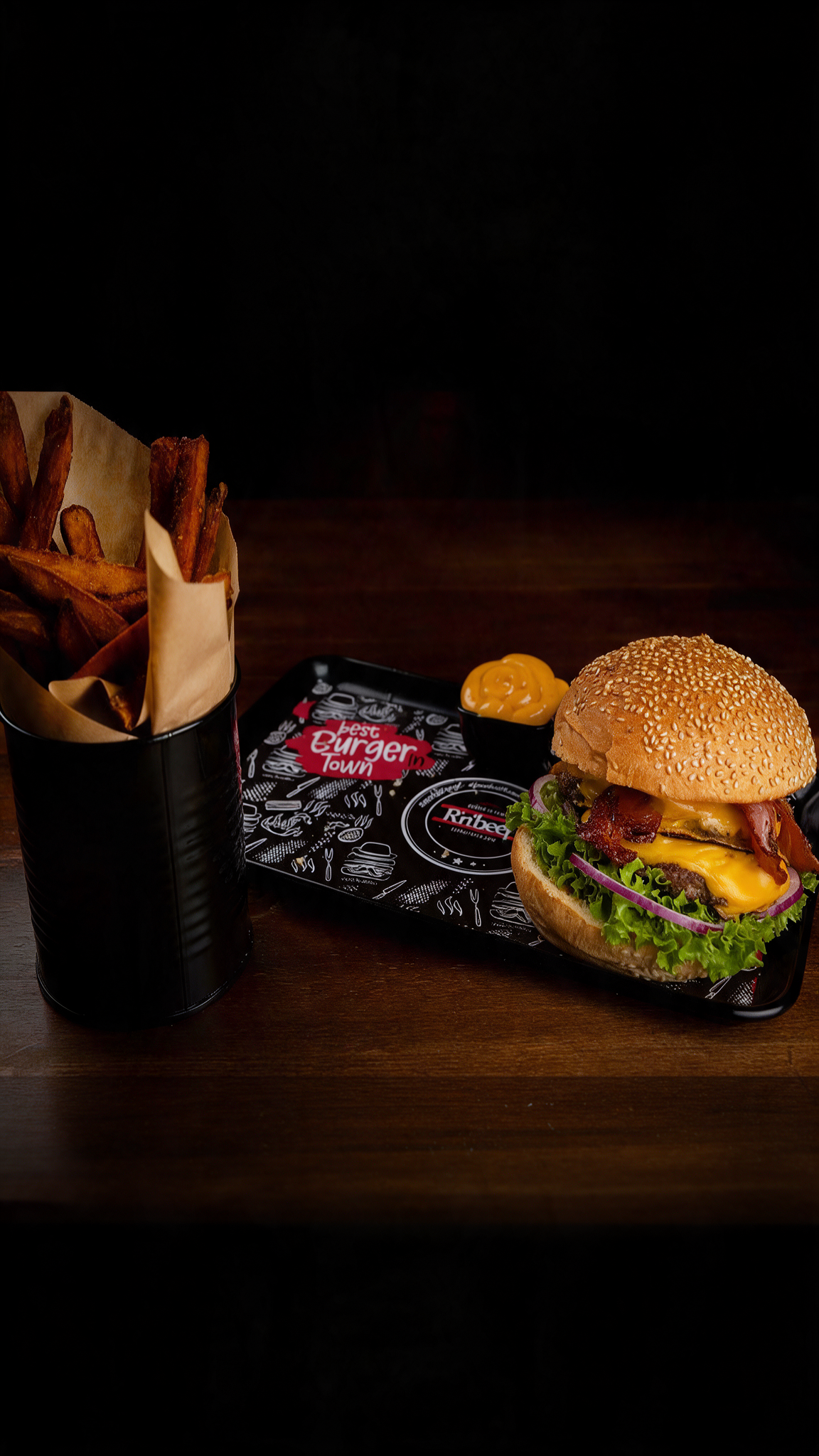 Burgermenü bei RnBeef in Essen mit frisch serviertem Burger, Pommes und Dip auf einem dunklen Holztisch
