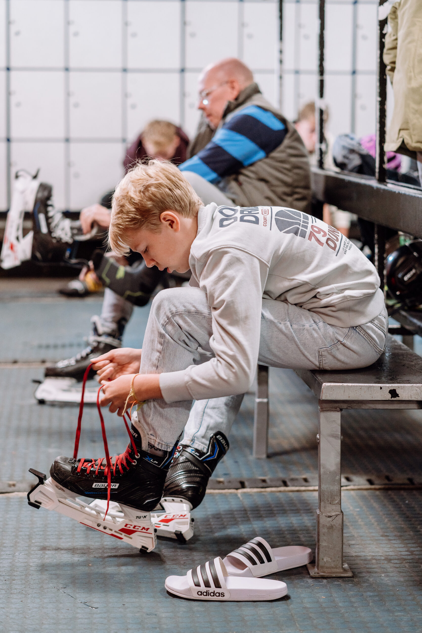 Besucher in der Eissporthalle Troisdorf beim Anziehen der Schlittschuhe vor der Eislaufzeit als Vorbereitung auf das gemeinsame Eislaufen