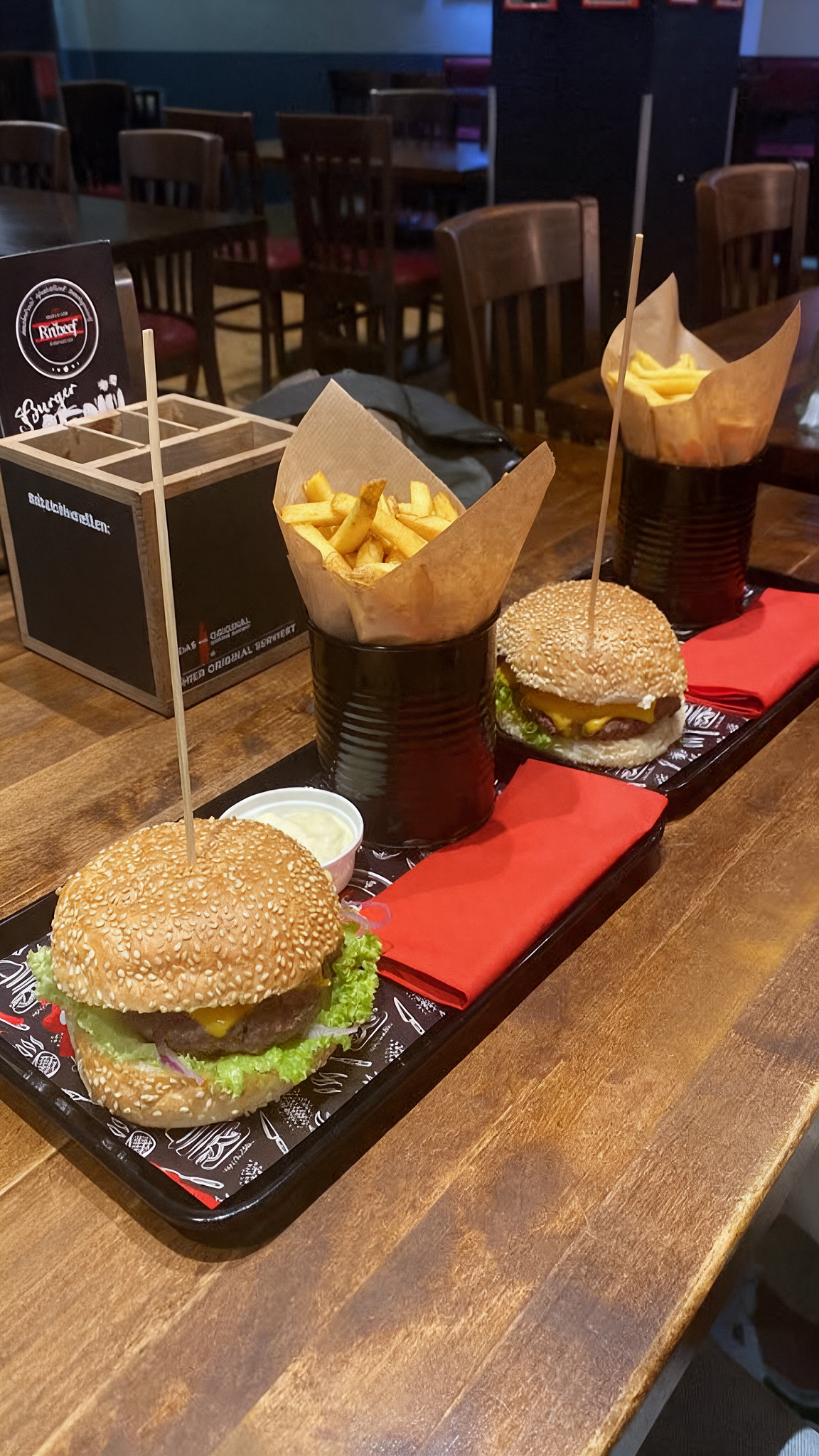 Burgermenü bei RnBeef in Krefeld mit zwei frisch servierten Burgern, Pommes in Tüten und Dips auf einem Tisch im Restaurant