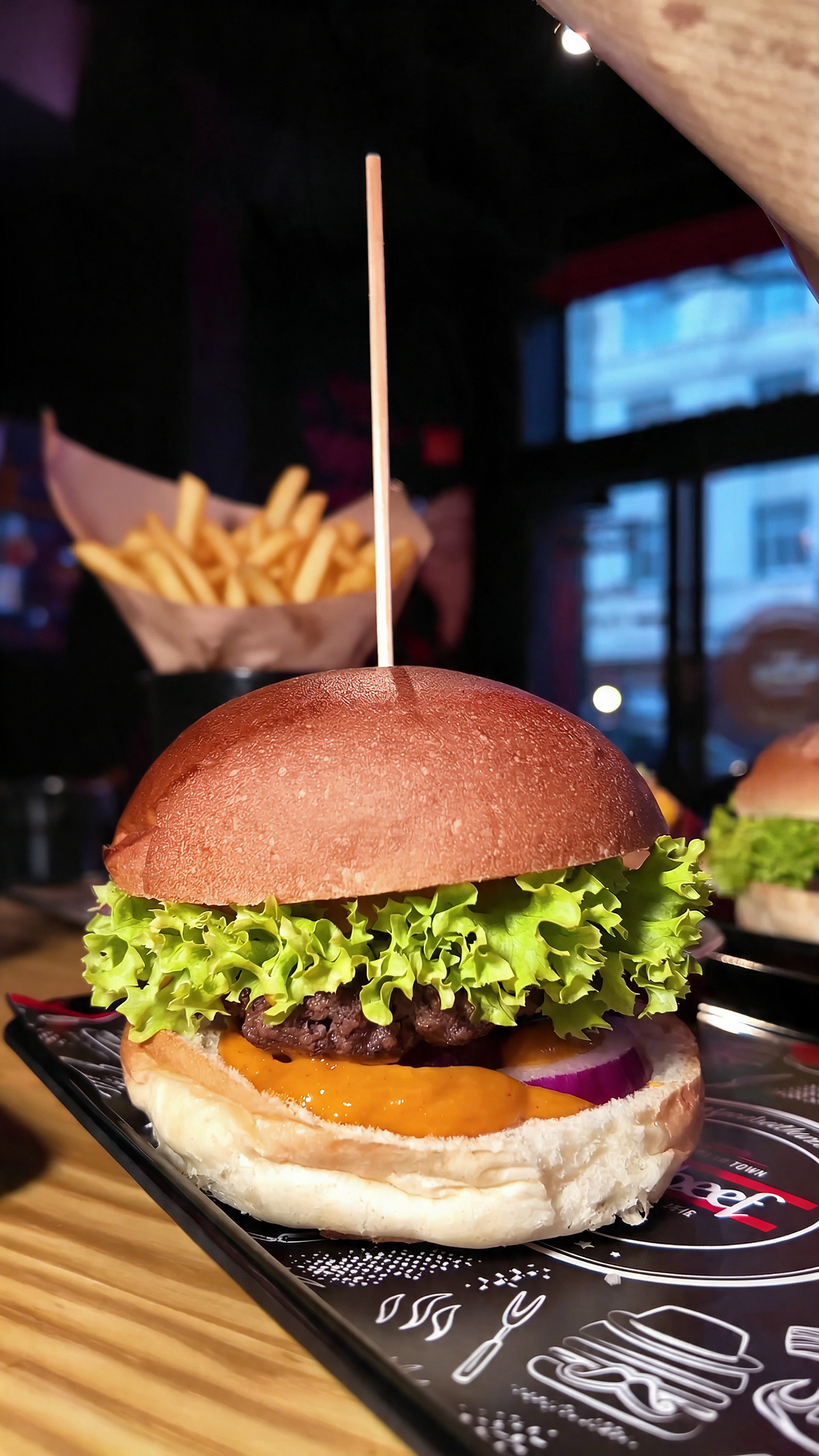Burger bei RnBeef in Marl als Nahaufnahme mit Rindfleisch Patty, Salat, Tomate, Zwiebeln und Pommes im Hintergrund